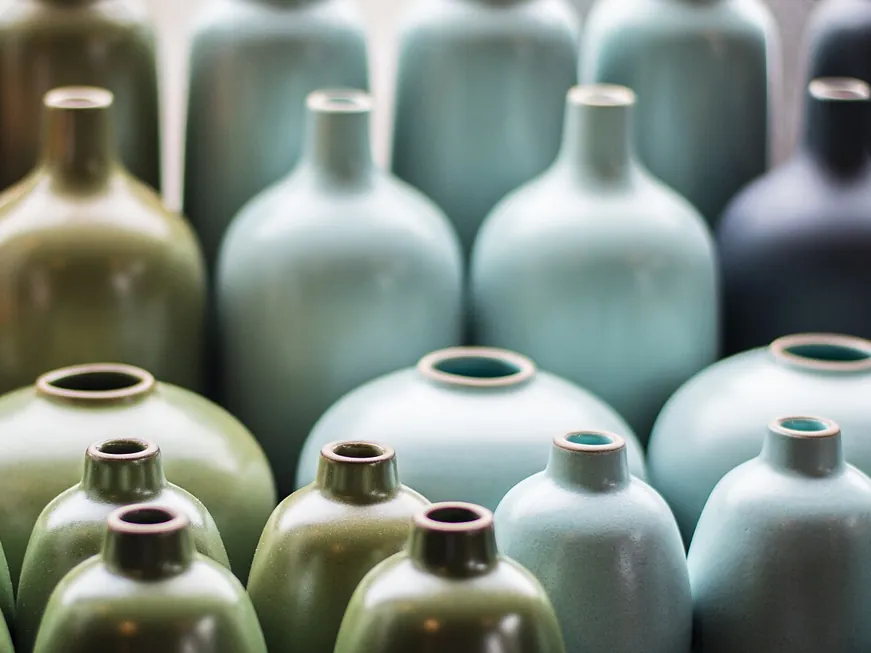 Rows of glazed stoneware bud vases in sage, blue and olive