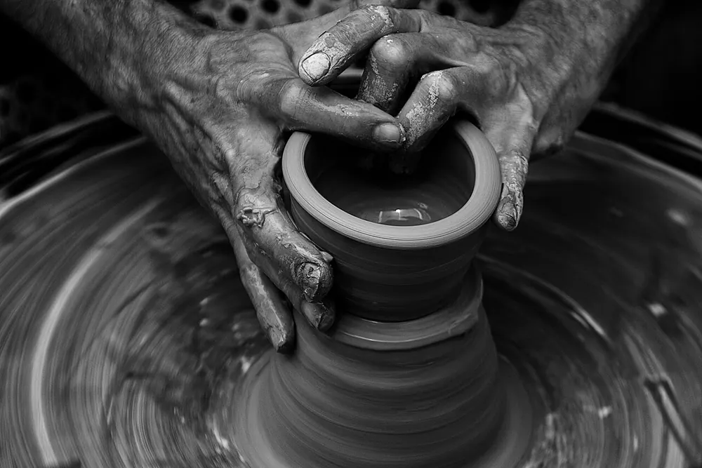 Close-up of hands pulling up the wall of a pot on the wheel
