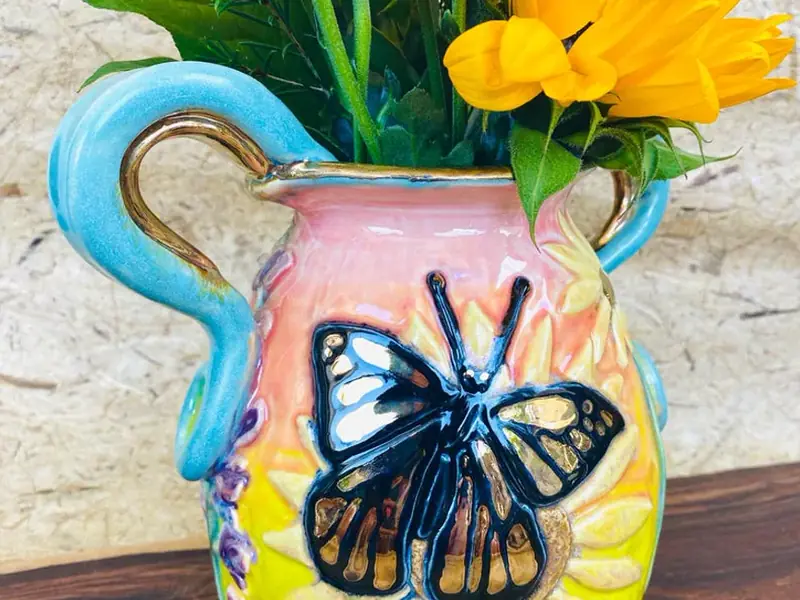 Handmade ceramic vase with a painted butterfly, filled with sunflowers, from Evers Art Shop